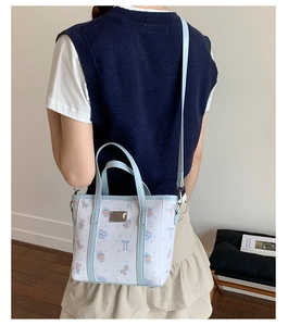 Detail of printed light blue tote bag with bear pattern worn by a model in casual style