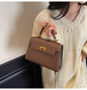 Detailed shot of brown cross-pattern leather kelly bag with gold clasp and top handle