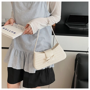 Detailed view of cream woven leather shoulder bag featuring a decorative ribbon bow accent