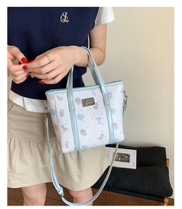 Detail of white leather tote bag with blue trim and cute cartoon bear patterns