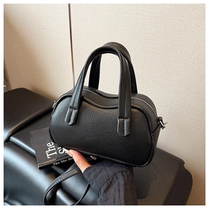 Détail du sac à main en cuir grainé noir avec poignée ondulée et fermeture éclair argentée