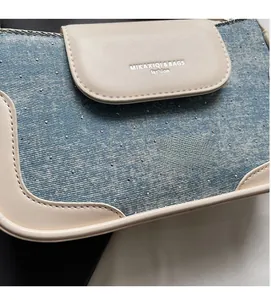 Detail of blue denim and white leather patchwork handbag with silver rhinestones