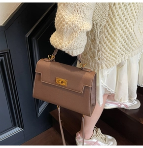 Detail of a brown lychee pattern leather handbag with golden metal rotating lock and strap