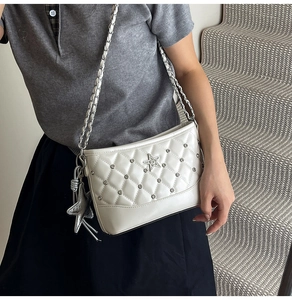 Detail of white quilted underarm bag with silver rhinestone star and metal chain strap