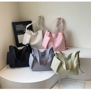 Detail view of five waffle-textured tote bags in soft colors on a white tiered display