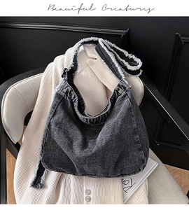 Dettaglio della borsa tote in denim nero con bordi sfrangiati su blazer bianco