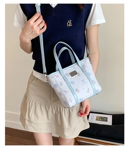 Detail showing the light blue bucket bag with cartoon bear print worn on the shoulder