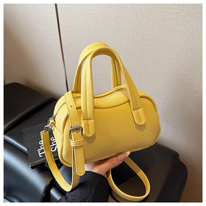 Détail du sac Boston en cuir jaune avec motif litchi et finitions métalliques argentées