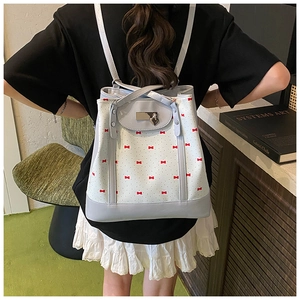Detail of light blue floral backpack with red bows shown on model in home setting