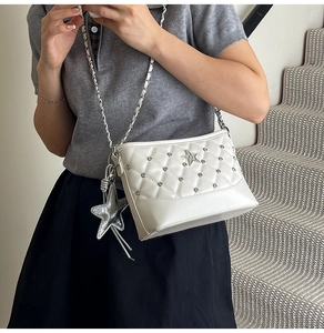 Close-up of white quilted crossbody bag with star charms and silver chain strap