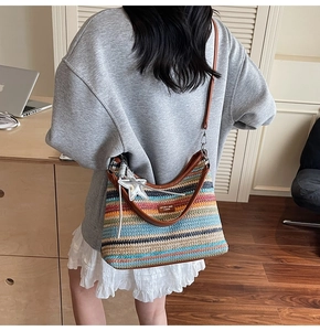 Détail d'un sac en paille tressée à rayures colorées avec des finitions en cuir marron chic