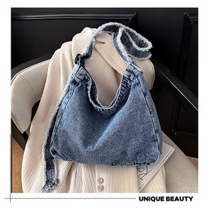 Dettaglio della borsa hobo in denim blu con bordi sfrangiati e tracolla con fibbia regolabile