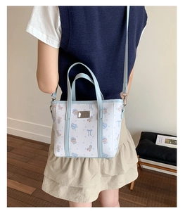 Detail of printed bucket bag showing adjustable shoulder strap on a female model