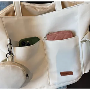 Detail of white canvas tote bag featuring large front pockets and a round coin purse