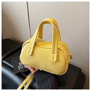 Détail du sac à main jaune en cuir grainé avec fermeture éclair et deux poignées hautes
