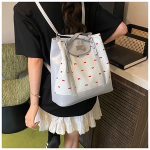 Detail of floral tote bag featuring red bow patterns and a heart pendant charm