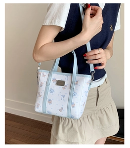 Detail of blue cartoon bear print tote bag with silver logo plate and shoulder strap