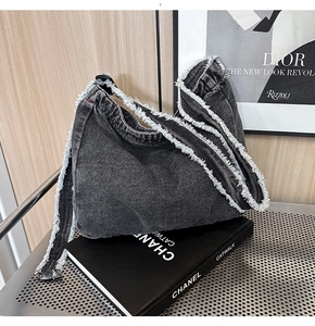 Dettaglio della borsa a tracolla in denim nero lavato con bordi sfilacciati e stile hobo