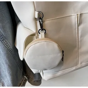 Detail of a round canvas coin purse with a black carabiner attached to a backpack