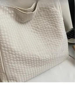 Close-up of beige waffle knit tote bag fabric showing texture and soft material detail