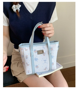 Close-up of light blue bucket bag with cute cartoon bear prints and silver metal logo