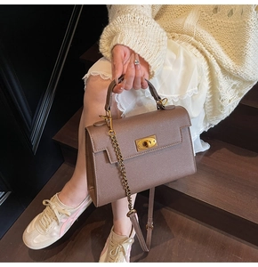 Close-up of litchi grain leather handbag with gold twist lock and chain strap