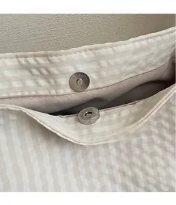 Detailed close-up of a sturdy magnetic snap closure on a beige checkered canvas tote bag