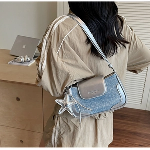 Detail of blue denim and silver leather patchwork handbag with a star pendant