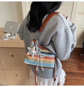 Détail d'un sac en paille tressée à rayures colorées avec breloque étoile et bandoulière en cuir