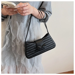 Close-up of black woven shoulder bag featuring a stylish decorative bow and leather strap
