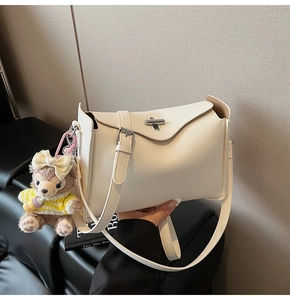 Detail of white lychee leather texture with silver metal turn-lock and cute bear charm