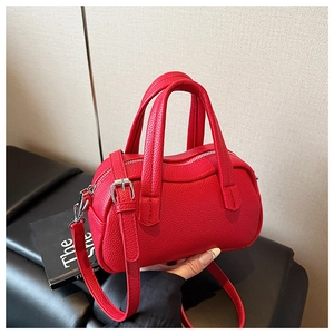 Détail du sac à main rouge en cuir grainé avec fermeture argentée et bandoulière réglable