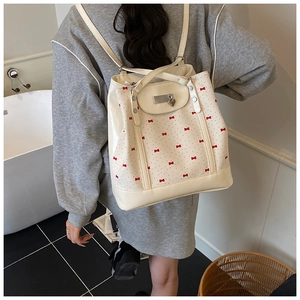 Close-up of cream floral tote bag with red bow pattern and silver heart-shaped lock detail