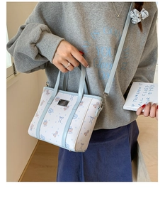 Detail of blue bear pattern bucket bag with leather texture and metal plate logo