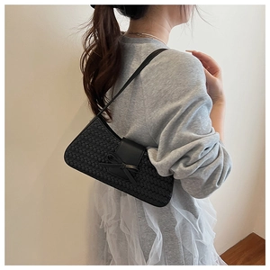 Detail view of black woven underarm bag with decorative bow and leather strap