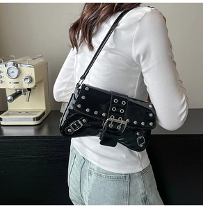 Detalle de bolso bandolera de charol negro con remaches plateados y estilo motero elegante