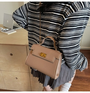 Detail of a brown lychee pattern leather handbag with a gold twist lock and chain strap