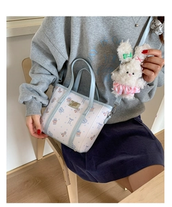 Detail of light blue bucket bag with cartoon bear print and plush rabbit charm