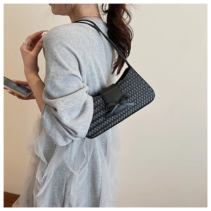 Détail de la texture en cuir tressé et du nœud élégant sur un sac à bandoulière noir chic