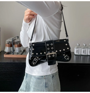 Detalle del bolso de hombro en charol negro con remaches plateados y hebilla metálica