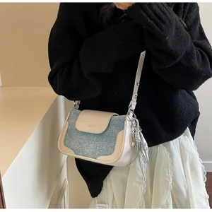 Detail of light blue glitter square crossbody bag with cream leather trim and silver charm