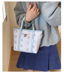 Close-up of the light blue tote bag featuring cute cartoon bear patterns and logo plate
