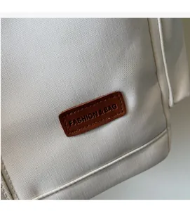 Detail of canvas texture and brown leather patch with FASHION & BAG lettering