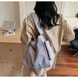 Detailed back view of a spacious light blue checkered tote bag worn as a shoulder bag