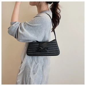 Detail of woven black shoulder bag with a stylish bowknot on a minimalist model profile