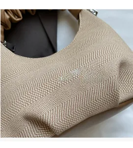 Detailed close-up of beige herringbone fabric texture and brown leather handle on a chic bag