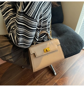 Close-up of khaki leather Kelly handbag with gold twist lock and metal chain strap
