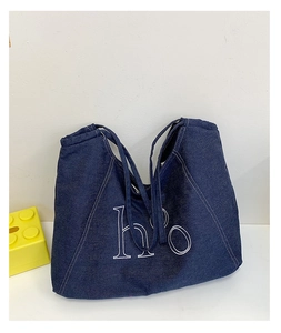 Detail of dark blue denim tote bag with white h'o letter embroidery and contrast stitching