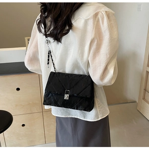 Quilted black crossbody bag with silver hardware shown on a model in a minimal setting