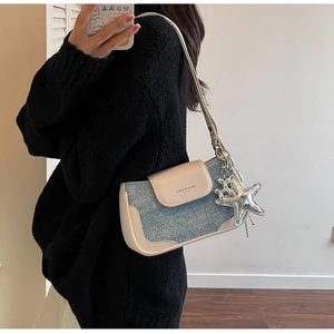 Detail of light blue denim crossbody bag with starfish and dog charms on a model